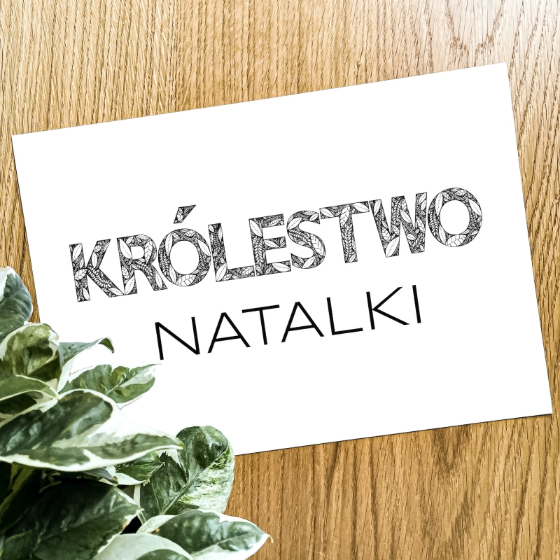 Plakat z imieniem dziecka na tle drewnianego stołu.