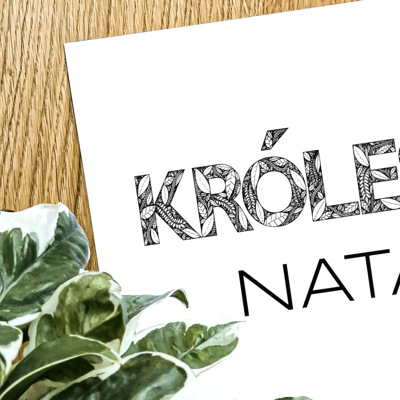 Plakat z liści na tle drewna.