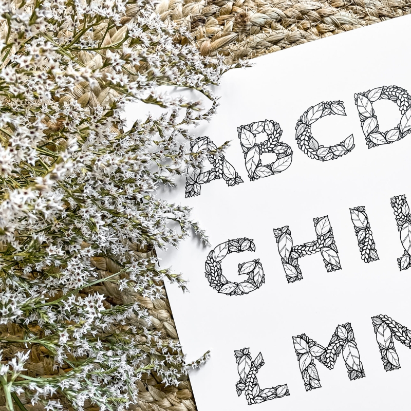 Plakat (alfabet) na tle dywanu wykonany z liści.