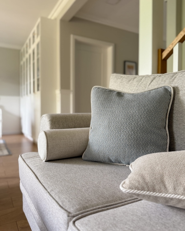 Błękitna poszewka na poduszkę ze sznurem GISELLE II 45x45 cm w aranżacji poduszek na kanapie.