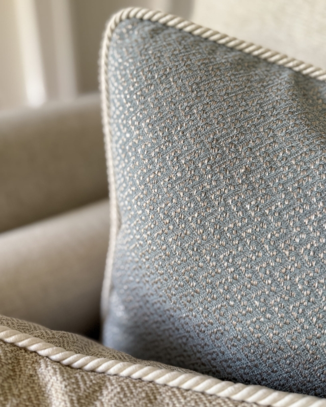 Błękitna poszewka na poduszkę ze sznurem GISELLE II 45x45 cm w aranżacji poduszek na kanapie - zbliżenie.