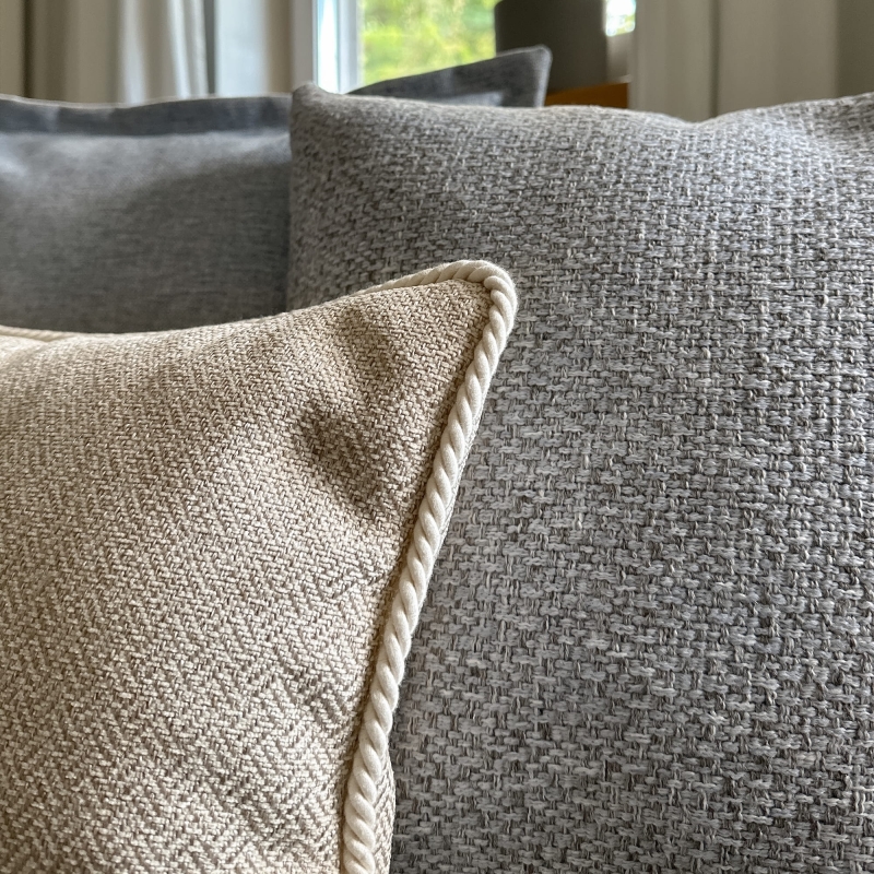 Błękitna poduszka z tkaniny o grubym splocie AZURE - 45x45 cm w aranżacji na kanapie.