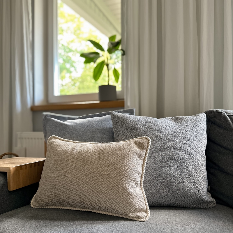 Błękitno-beżowy zestaw poduszek na kanapie.