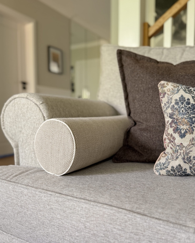 Lniana poduszka wałek w jodełkę LINEA w aranżacji na kanapie.