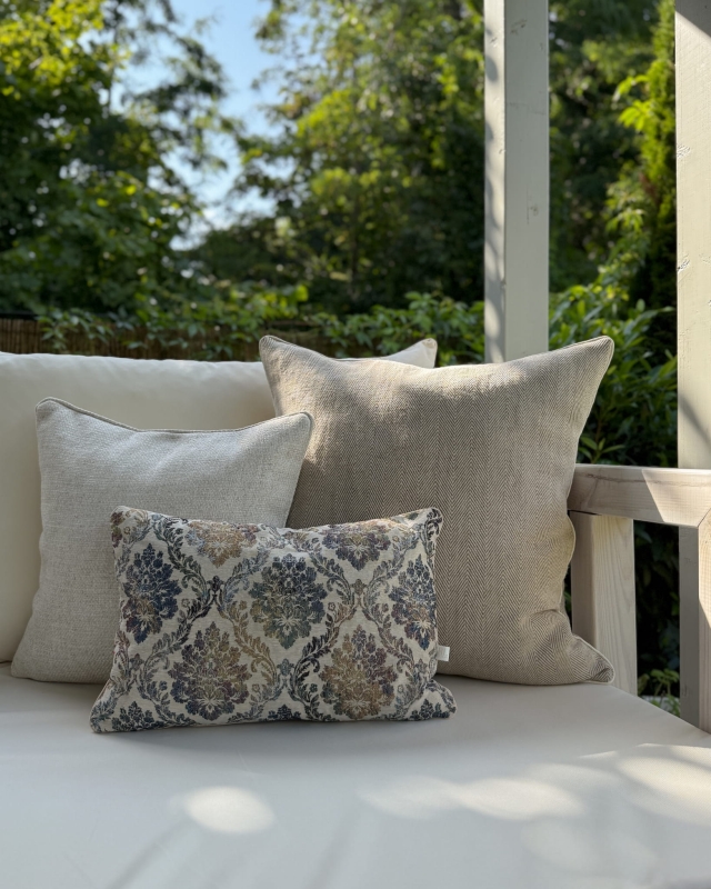 Beżowy zestaw poduszek ze wzorzystą, małą poduszką na kanapie na tarasie.