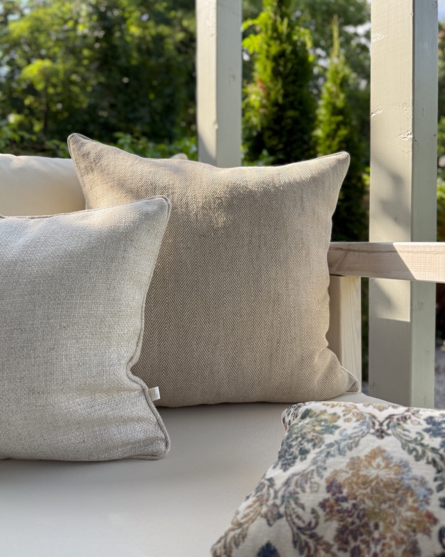 Beżowy zestaw poduszek ze wzorzystą, małą poduszką na kanapie na tarasie.
