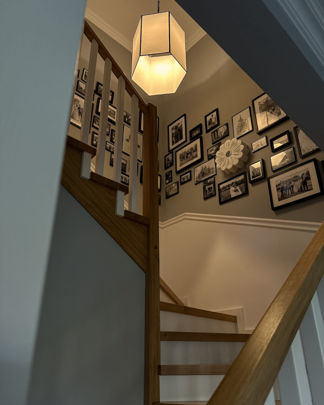 Duży biało-czarny abażur sześciokątny do lampy wiszącej GABIA 52 cm w aranżacji na klatce schodowej.