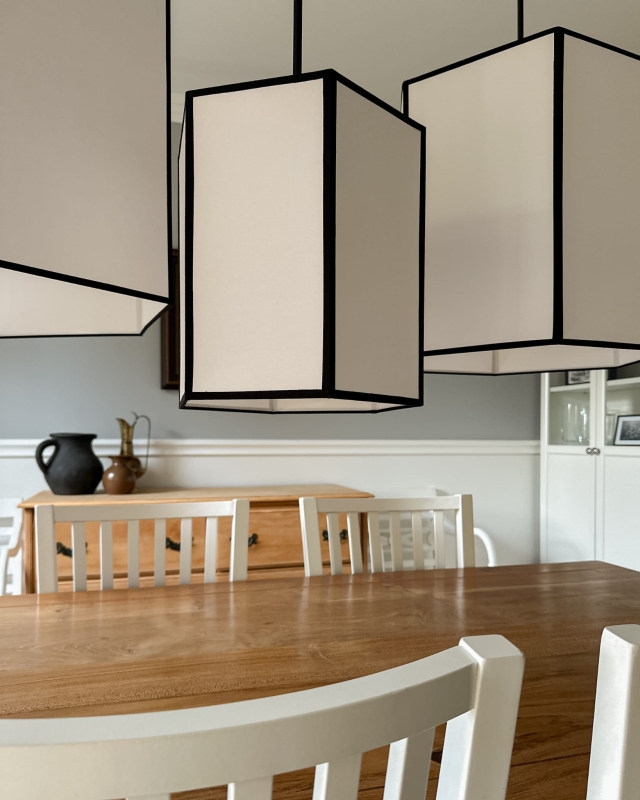 Długa biało-czarna sześciokątna lampa wisząca na łańcuchu GABIA I w aranżacji z pozostałymi lampami z kolekcji.