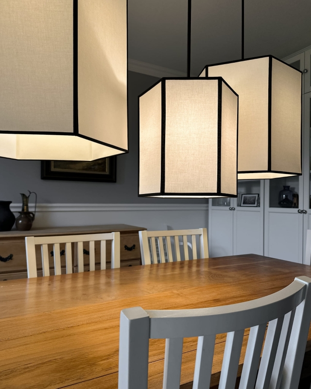 Długa biało-czarna sześciokątna lampa wisząca na łańcuchu GABIA I w aranżacji z pozostałymi lampami z kolekcji.