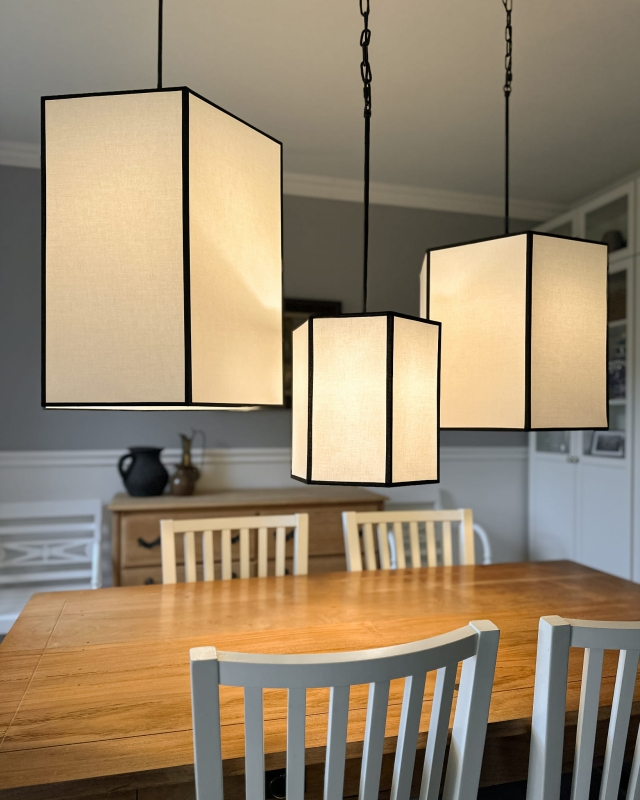 Długa biało-czarna sześciokątna lampa wisząca na łańcuchu GABIA I w aranżacji z pozostałymi lampami z kolekcji.