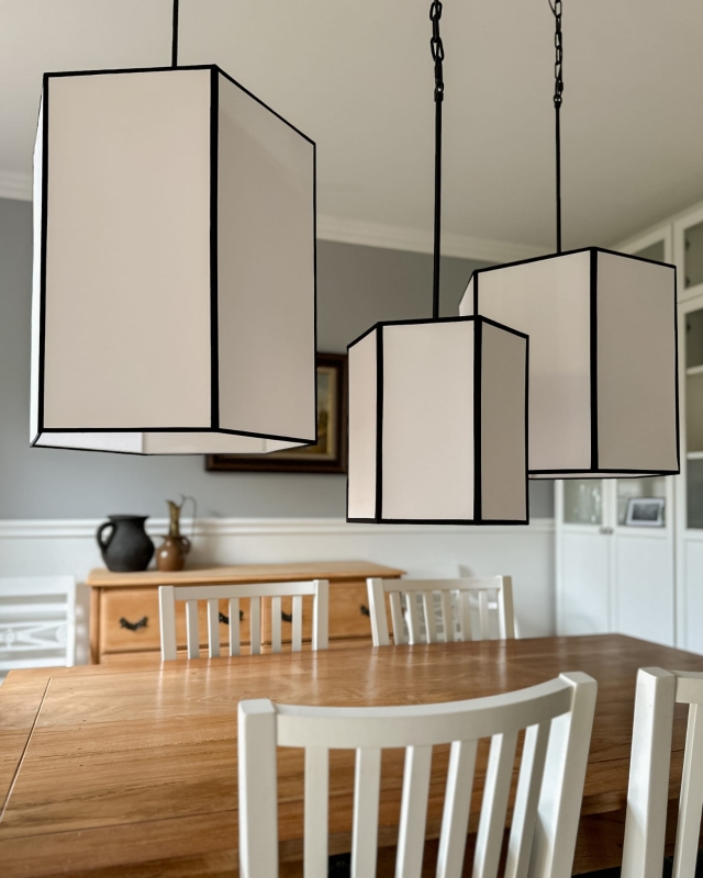 Długa biało-czarna sześciokątna lampa wisząca na łańcuchu GABIA III w aranżacji z pozostałymi lampami z kolekcji.