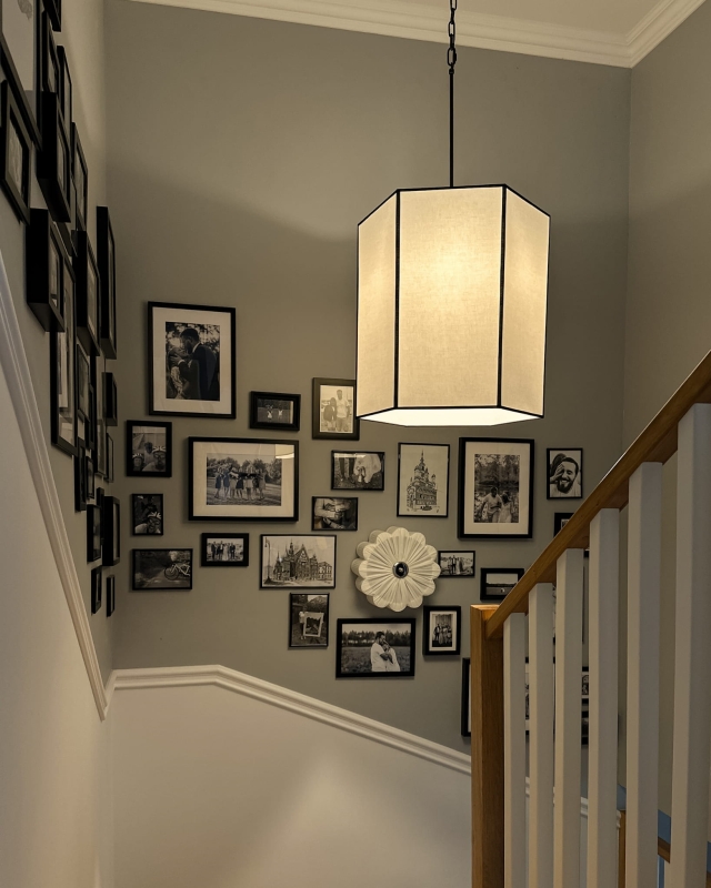 Długa biało-czarna sześciokątna lampa wisząca na łańcuchu GABIA III w aranżacji na klatce schodowej.