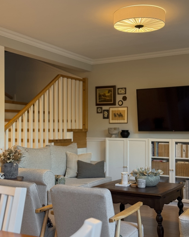 Duża lampa sufitowa w kolorze złamanej bieli w salonie PLISE BLACK III - zapalone światło.