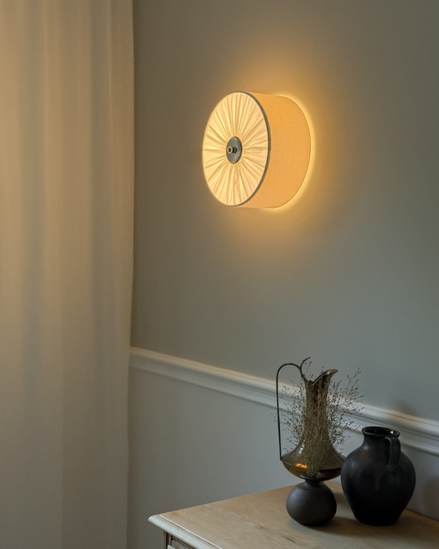 Elegancki kinkiet w kolorze złamanej bieli z niklowanym dekorem PLISE SILVER I - zapalone światło.