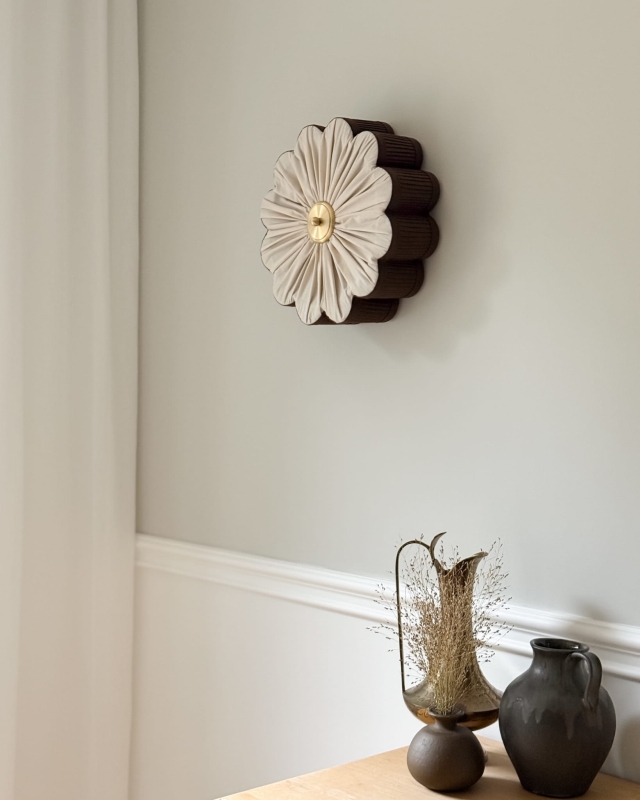 Brązowy kinkiet w kształcie kwiatu z mosiężnym dekorem PEONIA I zamontowany na ścianie.