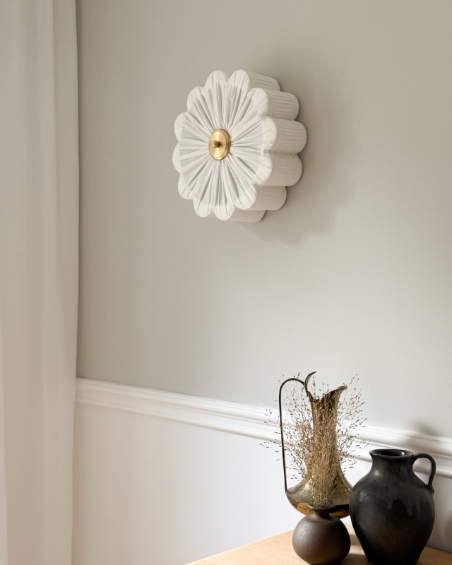 Biały kinkiet w kształcie kwiatu z mosiężnym dekorem PEONIA I śmietankowa biel w aranżacji na ścianie.
