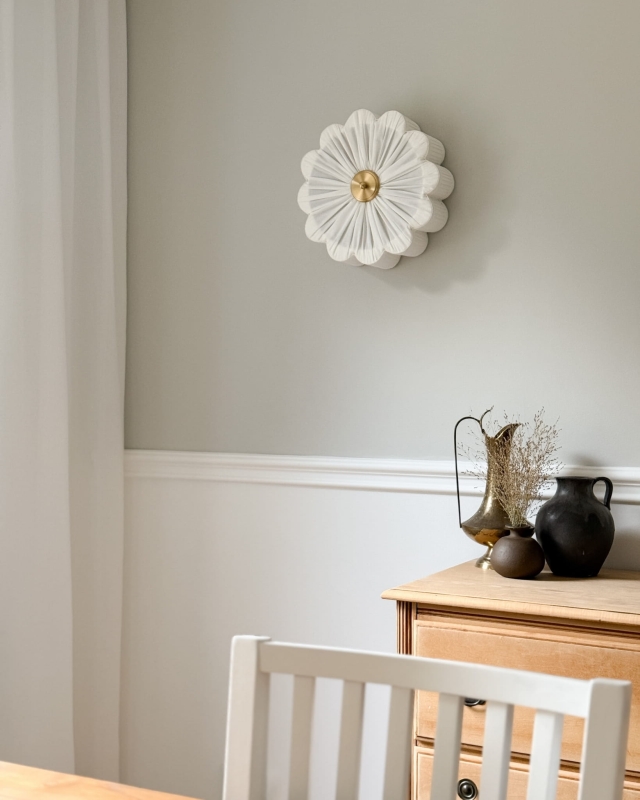 Biały kinkiet w kształcie kwiatu z mosiężnym dekorem PEONIA I śmietankowa biel w aranżacji na ścianie.