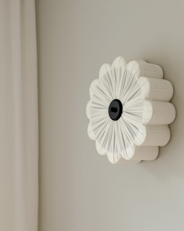 Biały kinkiet w kształcie kwiatu z czarnym dekorem PEONIA BLACK I śmietankowa biel w aranżacji na ścianie.