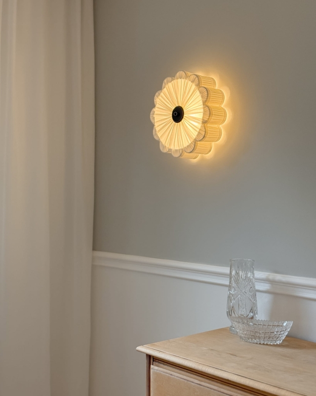 Biały kinkiet w kształcie kwiatu z czarnym dekorem PEONIA BLACK I śmietankowa biel w aranżacji na ścianie - zapalone światło.