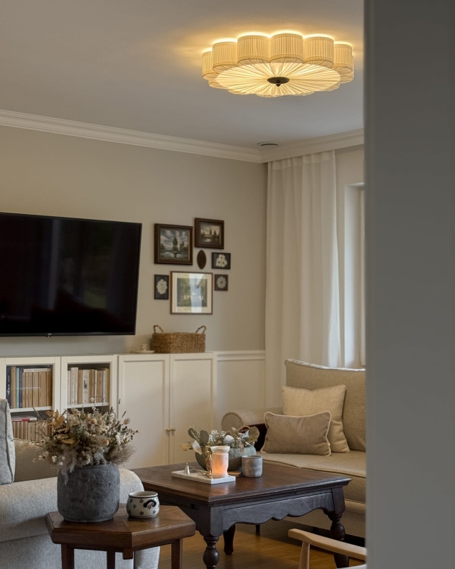 Duży biały plafon w kształcie kwiatu z czarnym dekorem PEONIA BLACK III śmietankowa biel w aranżacji jako główna lampa sufitowa do salonu - zapalone światło.