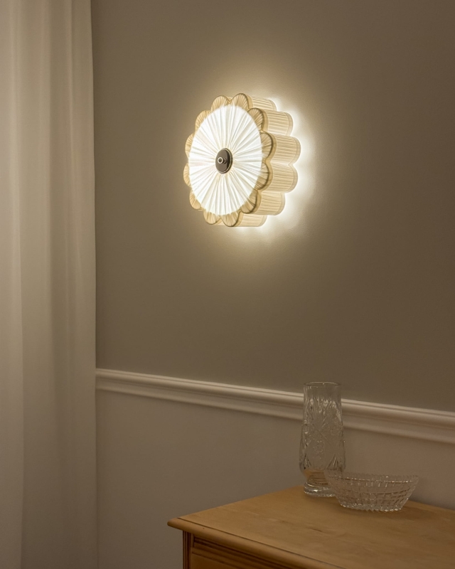 Mały biały kinkiet ze srebrnym niklowanym dekorem PEONIA SILVER I śmietanka w aranżacji na ścianie - zapalone światło.