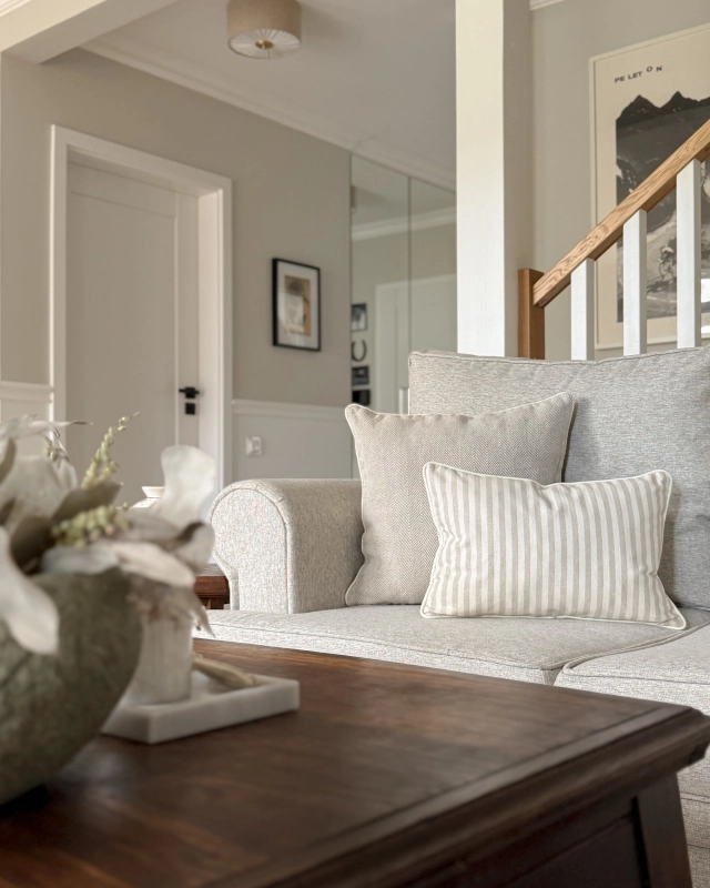 Prostokątna poduszka bawełniana w beżowo-kremowe paski SAND 30x45 cm w aranżacji na kanapie.