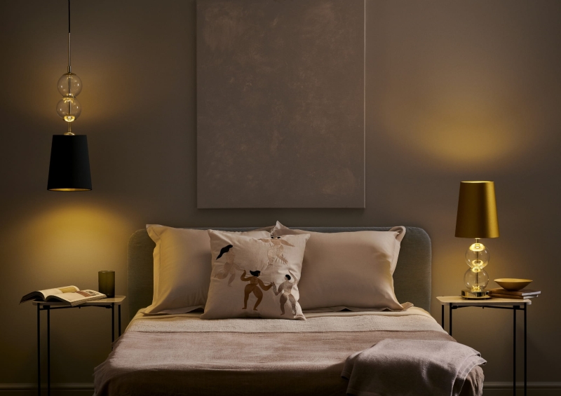 Złota lampka nocna z abażurem w kolorze starego złota COCO w połączeniu z czarną lampą wiszącą z tej samej kolekcji.