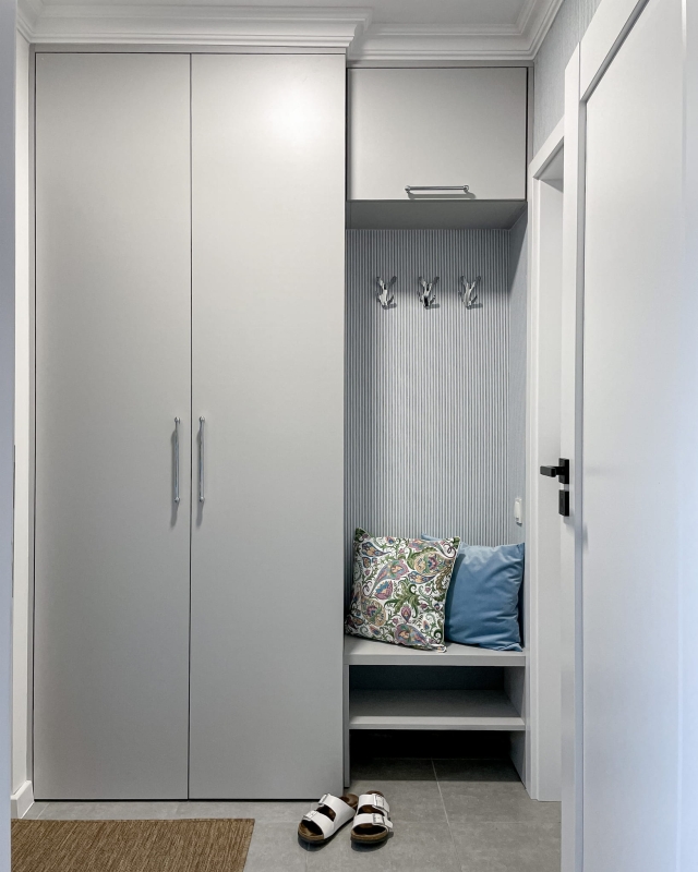 Poduszka welurowa w botaniczny wzór na ławce w wiatrołapie.