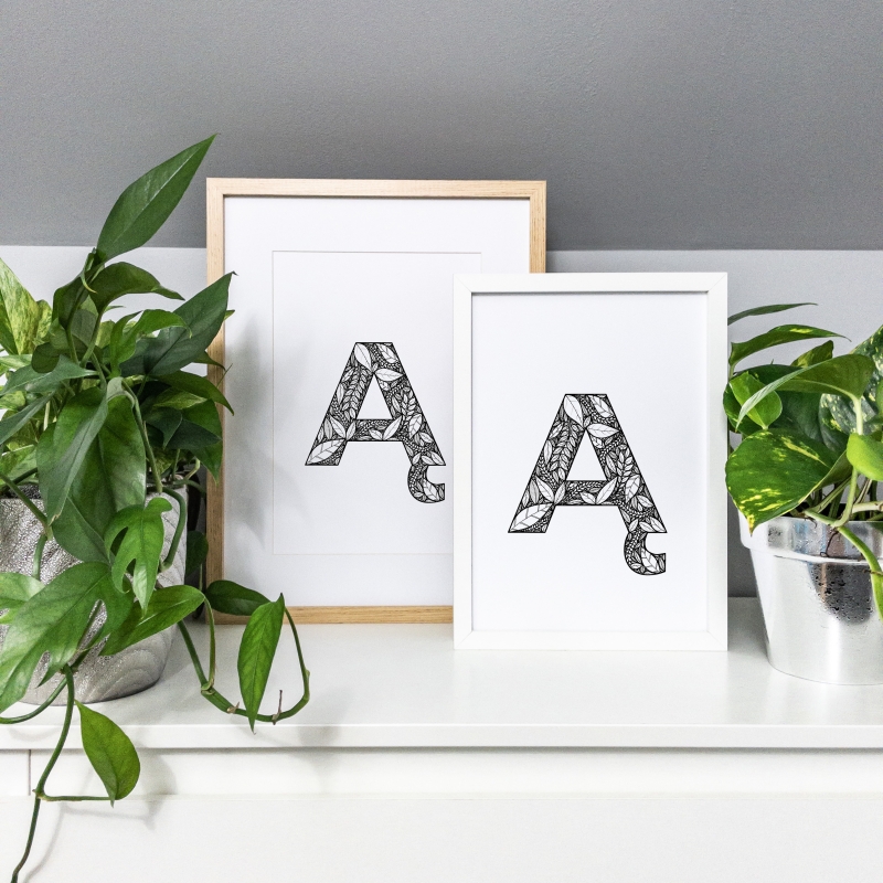 Plakaty w ramie z literą Ą na komodzie.