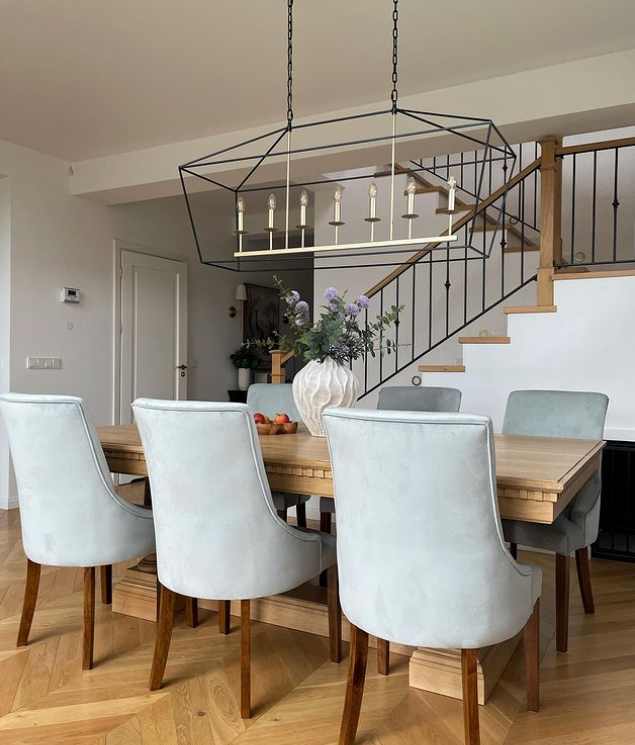 Duża lampa wisząca klatka czarno-złota GENTLE XL w aranżacji nad stołem.